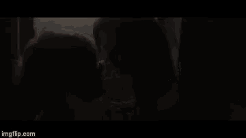 a man and a woman are kissing in front of a window .