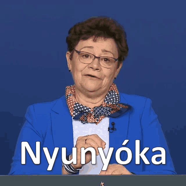 a woman in a blue jacket stands in front of a sign that says nyunyoka