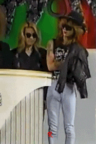 a woman wearing sunglasses is standing in front of a green wall