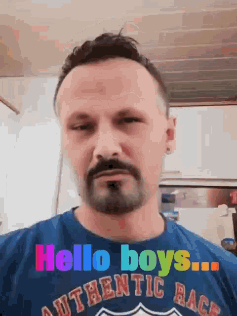 a man with a beard is wearing a blue shirt that says hello boys authentic race .