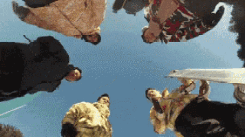 a group of people are standing in a circle looking up into the sky