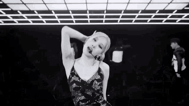a black and white photo of a woman dancing in a room .