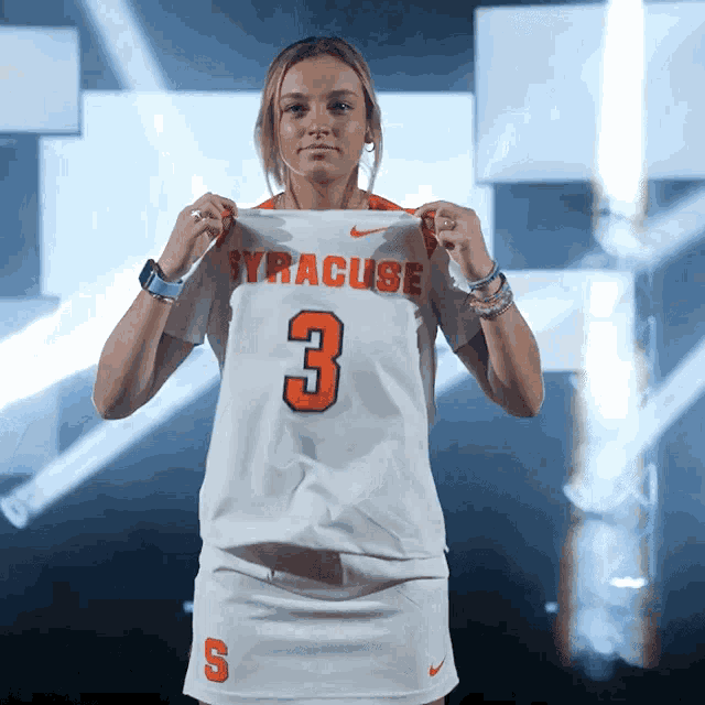 a woman holds up a syracuse jersey number 3