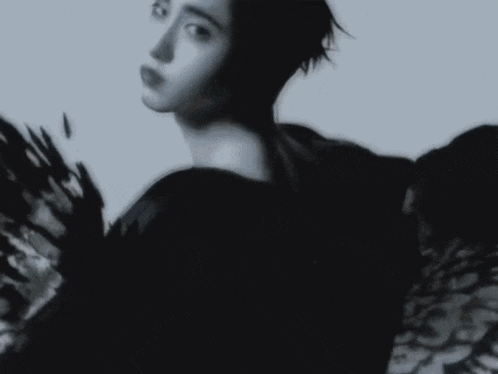 a black and white photo of a woman in a black dress with a blurred background .