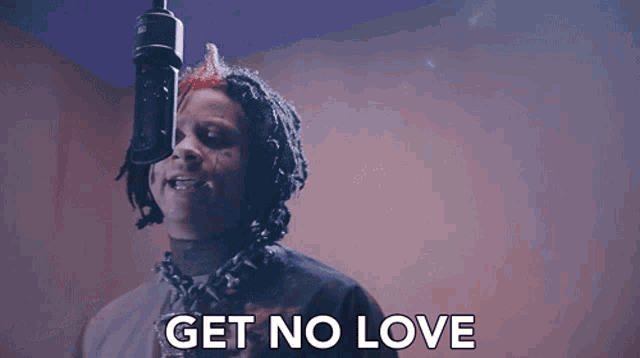 a man singing into a microphone with the words " get no love " below him