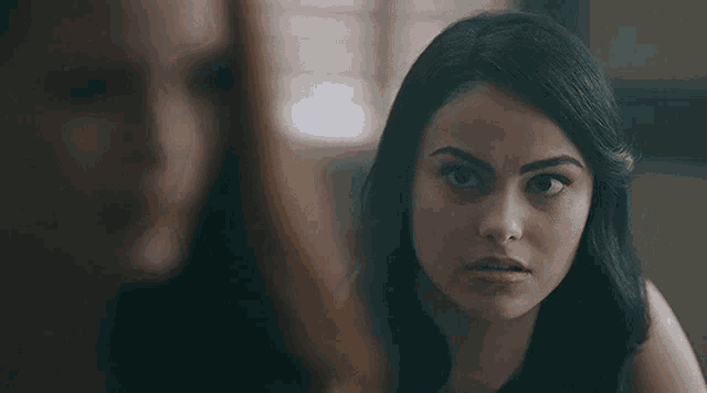 a woman with long black hair is looking at another woman .