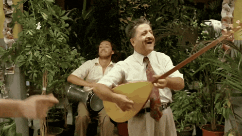 a man is playing a guitar while another man plays drums