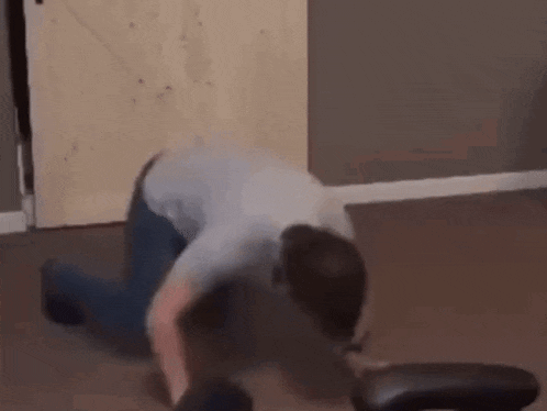 a man is kneeling on the floor in front of a chair .