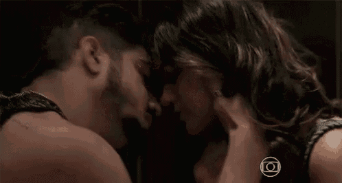 a man and a woman are kissing in front of a mirror in a dark room .