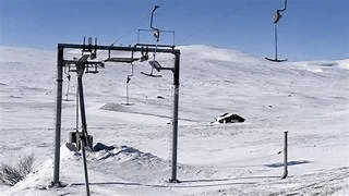 a ski lift is sitting on top of a snow covered slope .
