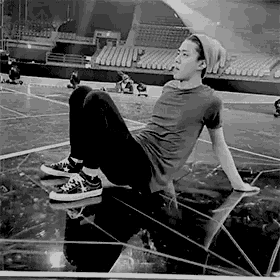 a black and white photo of a young man sitting on the floor in an empty stadium .