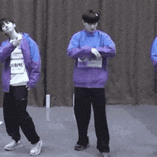 a group of young men are standing next to each other on a stage and dancing .