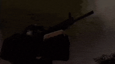a person wearing a helmet and goggles is holding a gun in the dark .