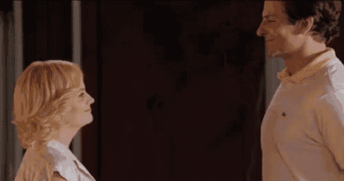 a man and a woman are standing next to each other and looking at each other .