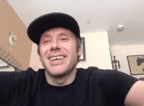 a man wearing a black hat and a black shirt smiles