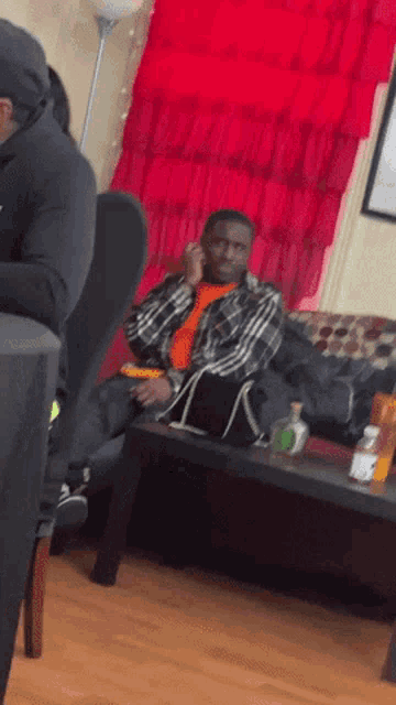 a man sitting on a couch talking on his phone