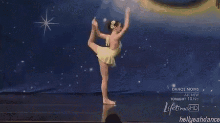 a girl in a yellow dress is doing a split on a stage