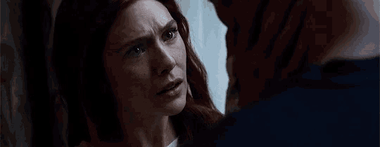 a man and a woman are looking at each other and the woman is looking at the man 's face .