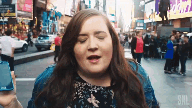 a woman singing on a street with a snl logo on the bottom right