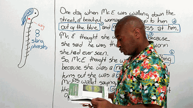 a man is reading a book in front of a white board with phrases written on it