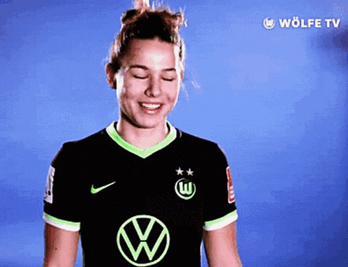 a woman wearing a black and green jersey with the vw logo on it