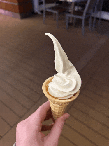 a person holding a cone of vanilla ice cream