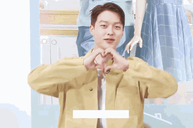 a man in a yellow jacket making a heart with his hands
