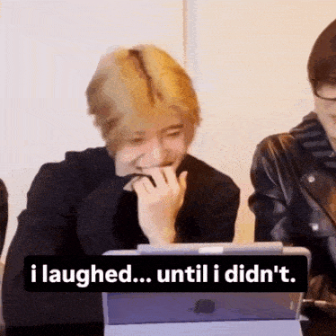 a man is laughing while sitting at a table with a tablet .