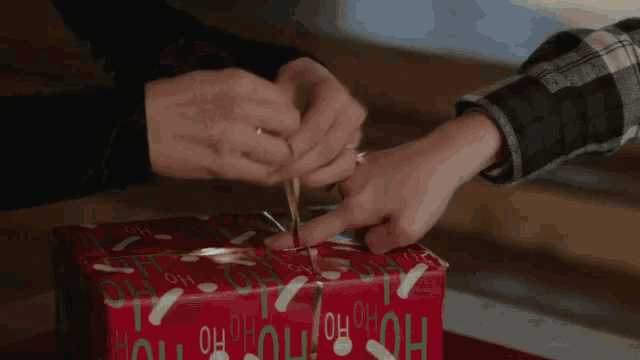 a woman and a young boy are wrapping christmas presents in a living room .