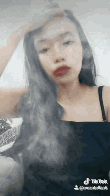 a woman with long black hair is smoking a cigarette