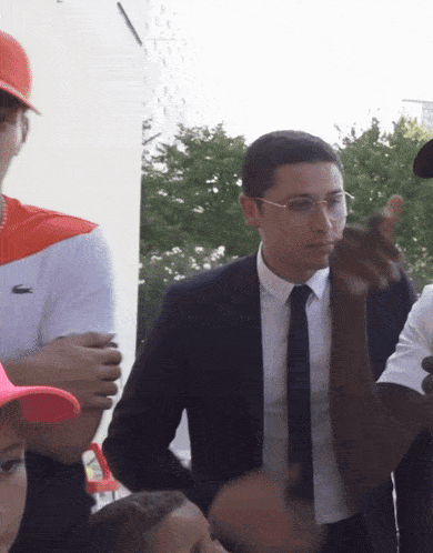 a man in a suit and tie is talking to another man in an orange hat