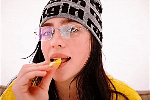 a woman wearing glasses and a beanie that says 90