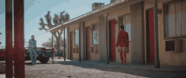 a woman in a red outfit stands in front of a building