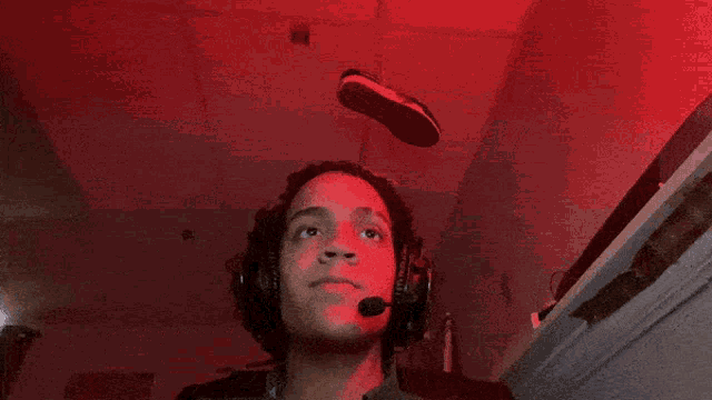 a man wearing headphones is looking up at a shoe that is flying in the air
