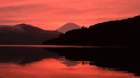 a sunset over a lake with a mountain in the background .