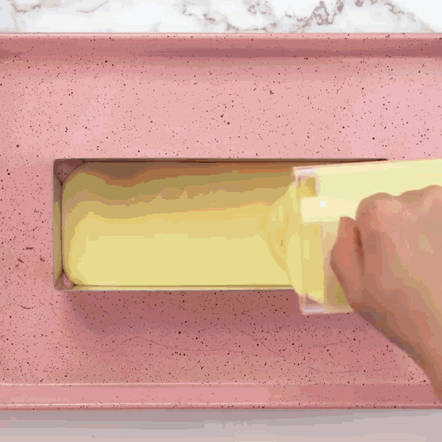 yellow liquid is being poured into a pink pan