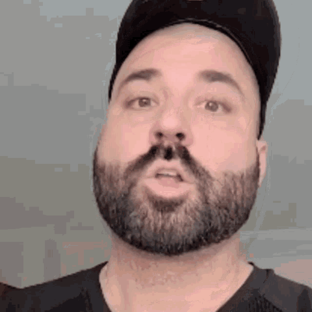 a man with a beard and hat is making a face .