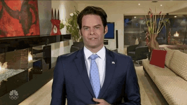 a man in a suit and tie is standing in front of a living room