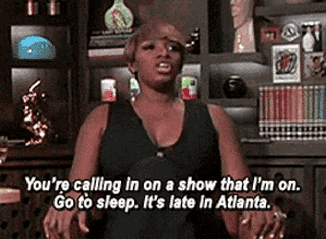 a woman is standing in front of a bookshelf and talking about a show she 's on .