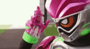 a close up of a person in a pink and green costume holding a bottle .