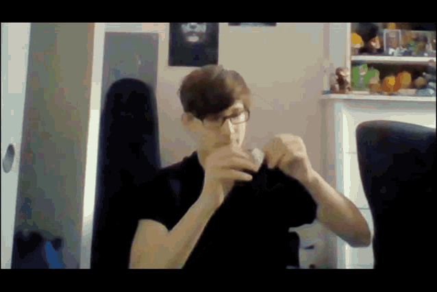 a man wearing glasses and a black shirt is sitting in front of a mirror