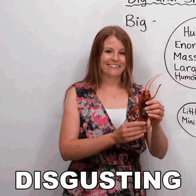 a woman is holding a lobster in front of a white board that says big disgusting