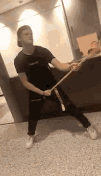 a man is holding a wooden stick in his hands and dancing on the floor .