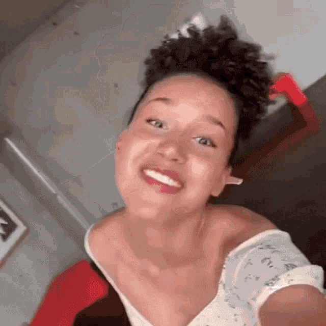 a woman with curly hair is taking a selfie and smiling for the camera .