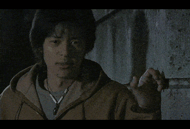 a man in a brown jacket is standing in front of a brick wall