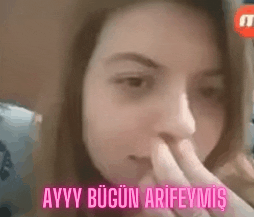 a close up of a woman covering her nose with her fingers .