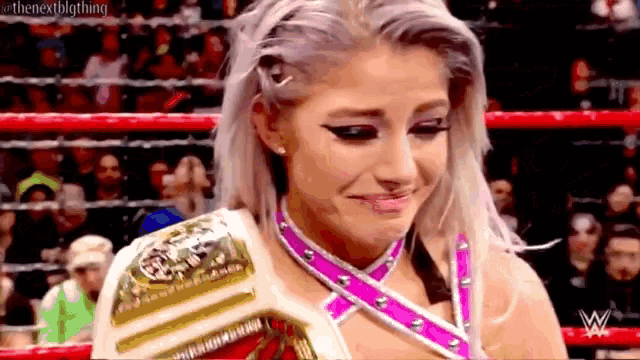 a woman is crying in a wrestling ring while wearing a wrestling belt .