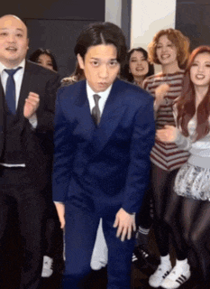 a man in a blue suit and tie is dancing with a group of people