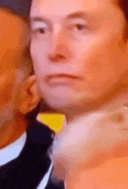a close up of a man 's face with a yellow sticker on his ear