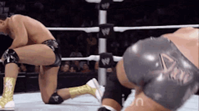 two wrestlers are kneeling down in a wrestling ring with the word icon on the bottom right